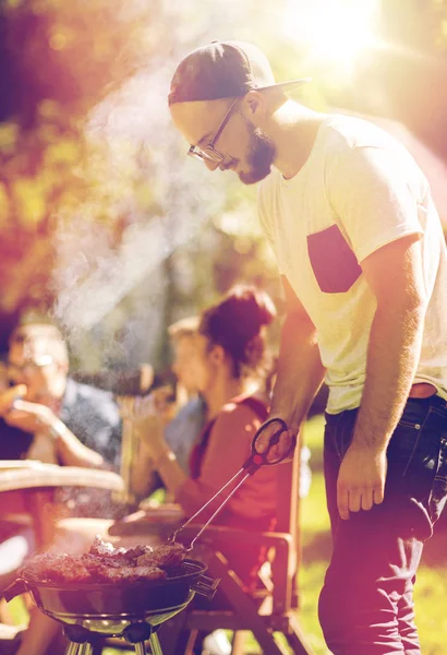 Hombre cocinar carne en barbacoa parrilla en la fiesta de verano —  Fotos de Stock