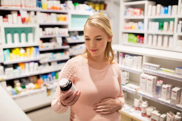 Gelukkig zwangere vrouw met medicatie bij apotheek — Stockfoto