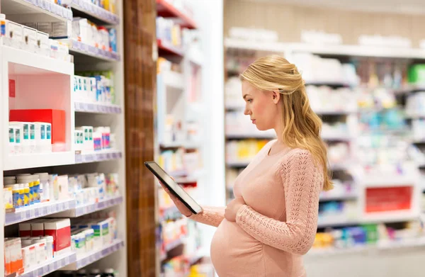 Zwangere vrouw met tablet pc bij apotheek — Stockfoto