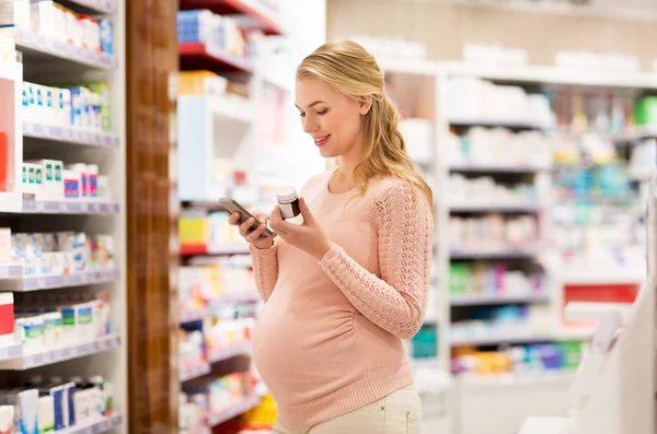 Gelukkig zwangere vrouw met medicatie bij apotheek — Stockfoto