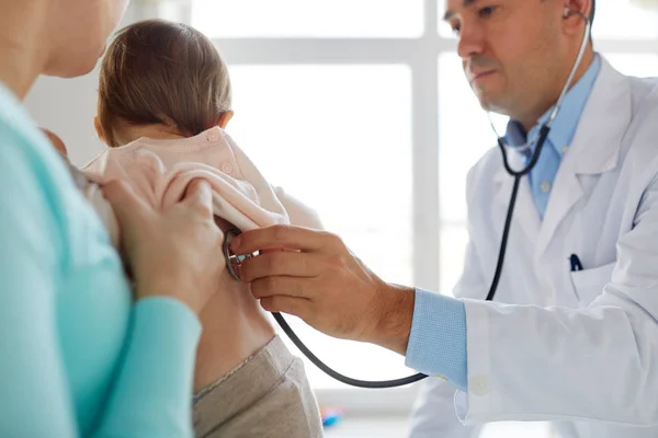 Läkare med stetoskop lyssnande baby på klinik — Stockfoto