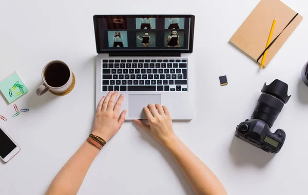 Vrouw handen met camera werken op de laptop aan tafel — Stockfoto