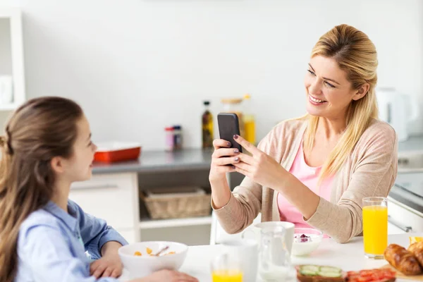 Mujer fotografiando hija por teléfono inteligente en casa —  Fotos de Stock