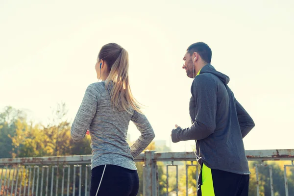 Feliz pareja con auriculares corriendo al aire libre — Foto de Stock