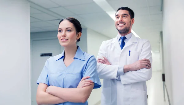 Smiling doctor in white coat and nurse at hospital — Stock Photo, Image