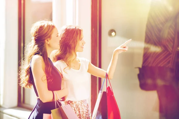 Mulheres felizes com sacos de compras na vitrine da loja — Fotografia de Stock