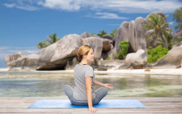 Twist poz kumsalda yoga yaparken kadın — Stok fotoğraf