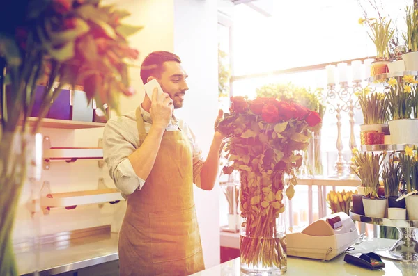 Homme avec smartphone et roses rouges au magasin de fleurs — Photo