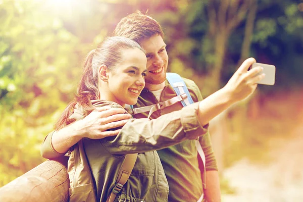 Casal com mochilas tirando selfie por smartphone — Fotografia de Stock