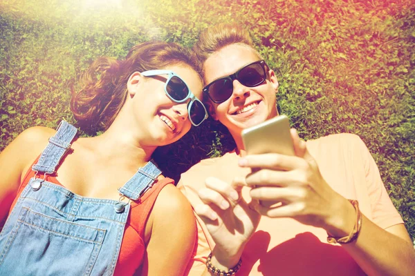 Szczęśliwa para nastoletnich smartphone, leżąc na trawie — Zdjęcie stockowe