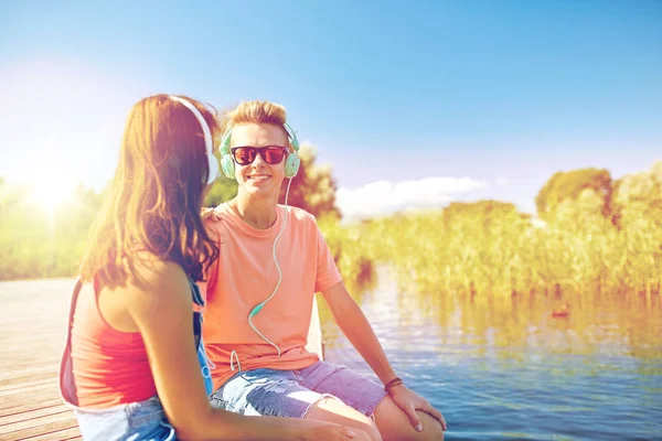 Feliz pareja adolescente con auriculares en la litera del río —  Fotos de Stock