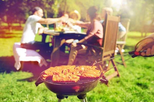 man cooking meat on barbecue grill at summer party