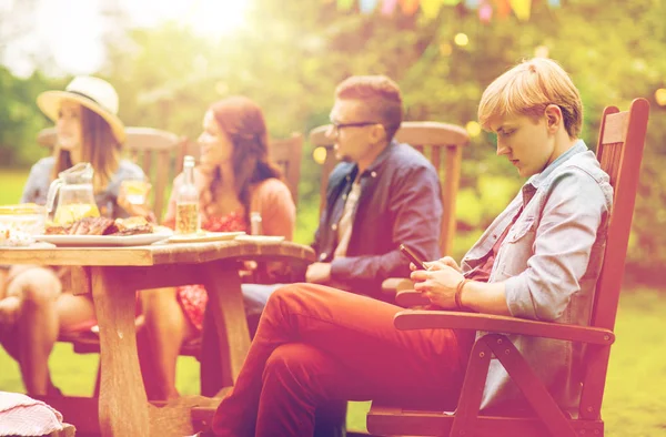 Man with smartphone and friends at summer party — Stock Photo, Image