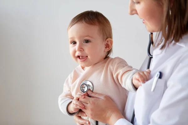 Médico con estetoscopio escuchando al bebé en la clínica — Foto de Stock