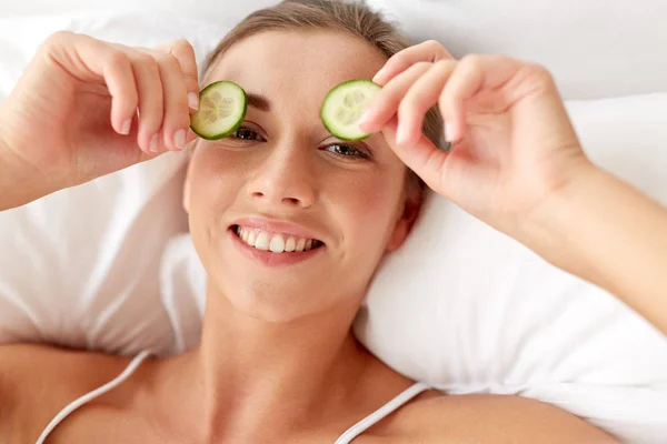 Beautiful woman applying cucumbers to eyes at home — Stock Photo, Image