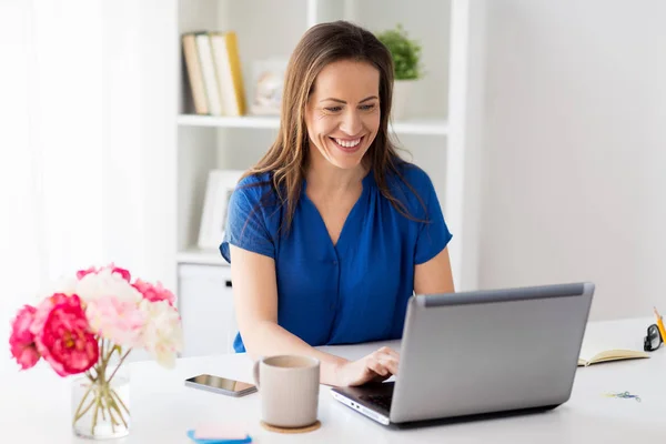 Mujer feliz con el ordenador portátil que trabaja en casa u oficina — Foto de Stock