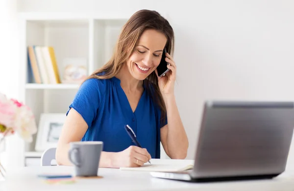 Mujer con bloc de notas llamando en el teléfono inteligente en la oficina — Foto de Stock