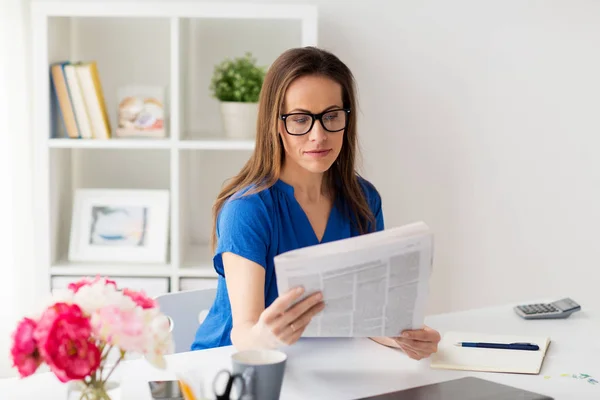 O femeie în ochelari citind ziare la birou — Fotografie, imagine de stoc