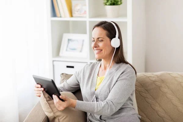 Mujer feliz con tablet pc y auriculares en casa — Foto de Stock