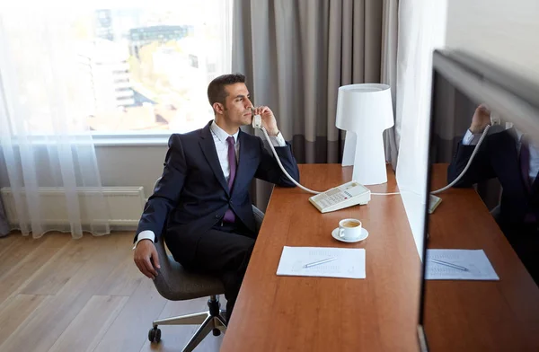 Homem de negócios chamando no telefone mesa no quarto do hotel — Fotografia de Stock
