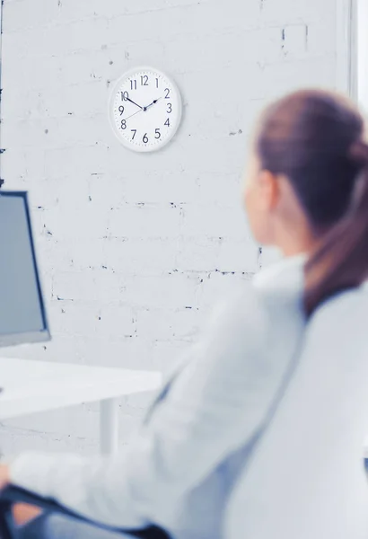 Mujer de negocios mirando el reloj de pared en la oficina — Foto de Stock