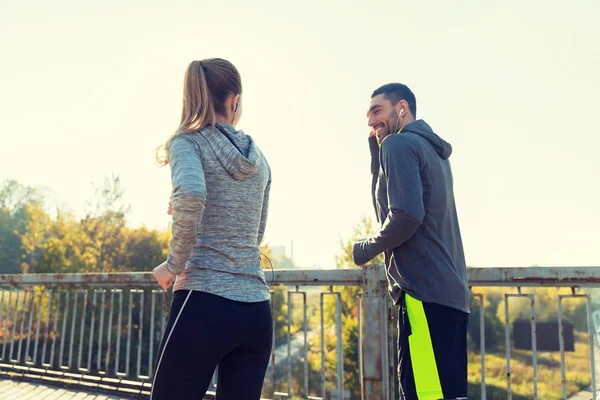 Feliz pareja con auriculares corriendo al aire libre —  Fotos de Stock