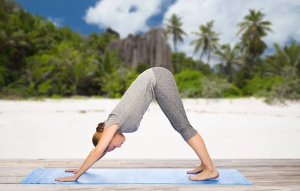 Vrouw doet yoga houding van de hond op strand — Stockfoto