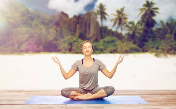 Женщина делает йогу медитации в позе лотоса на пляже — стоковое фото