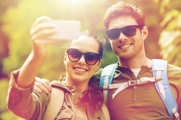 Couple with backpacks taking selfie by smartphone — Stock Photo, Image