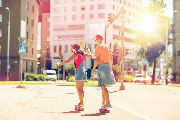 10代のカップルがスケートボードに乗って街を — ストック写真