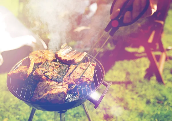 Man cooking meat on barbecue grill at summer party — Stock Photo, Image