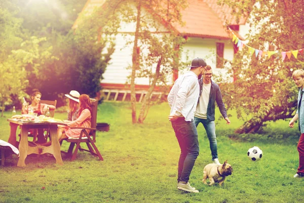 Friends playing football with dog at summer garden — Stock Photo, Image
