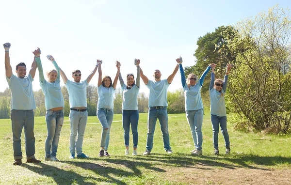 Grupp glada frivilliga hålla händer utomhus — Stockfoto