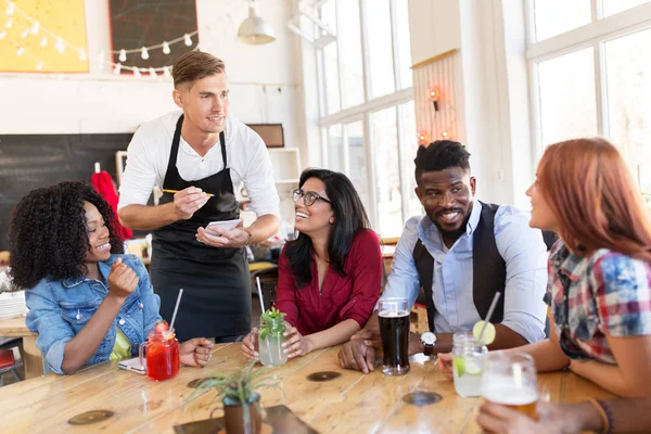 Cameriere e amici con menù e bevande al bar — Foto Stock