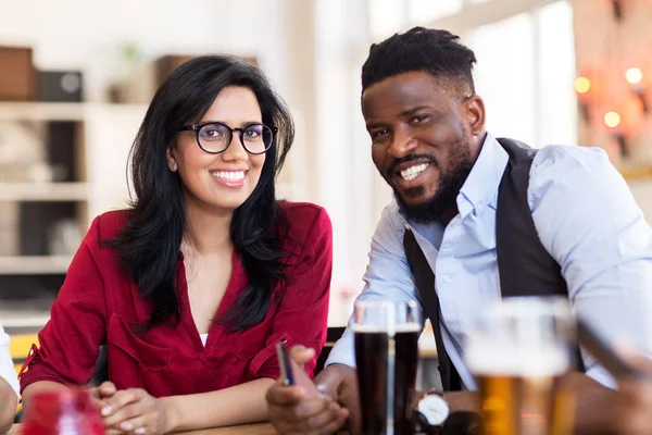 Щасливий чоловік і жінка зі смартфоном в барі — стокове фото