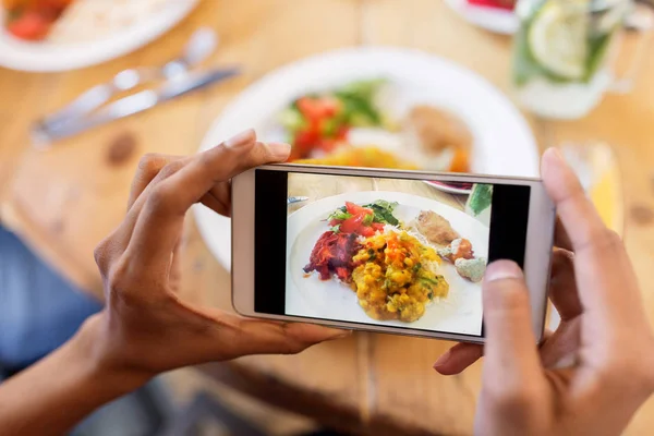 Mãos com smartphone retratando comida no restaurante — Fotografia de Stock