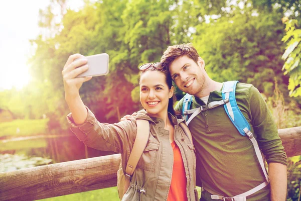 Para z plecakami biorąc selfie przez smartfona — Zdjęcie stockowe