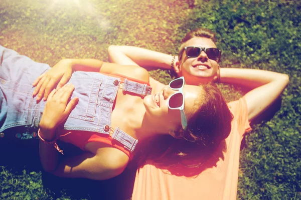 Feliz casal adolescente deitado na grama no verão — Fotografia de Stock