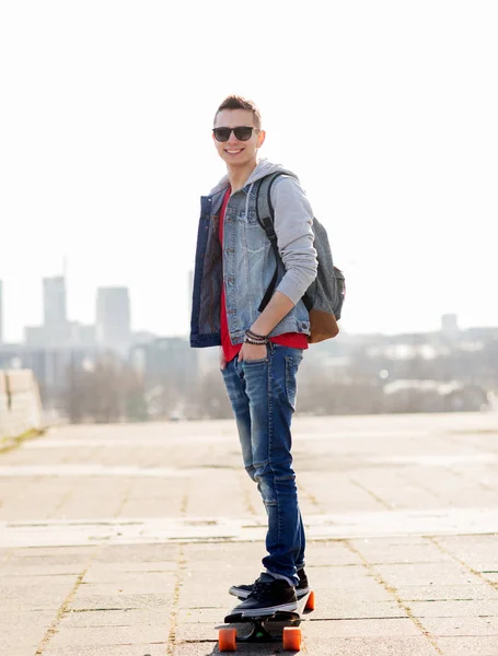 Happy young man or teenage boy riding on longboard — Stock Photo, Image