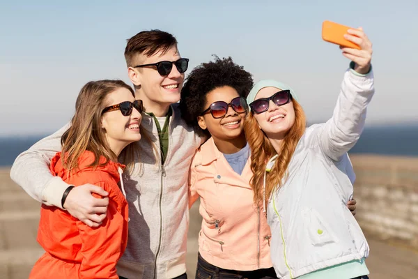 Amigos felices tomando selfie por teléfono inteligente al aire libre — Foto de Stock