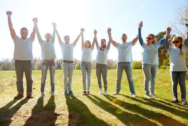 Grupo de voluntarios felices tomados de la mano al aire libre — Foto de Stock