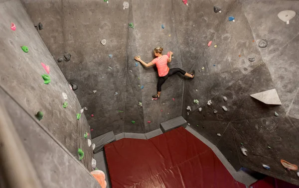 Jovem mulher exercitando na parede do ginásio de escalada interior — Fotografia de Stock