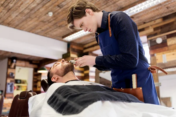 Homem e barbeiro com barba de corte aparador no salão — Fotografia de Stock