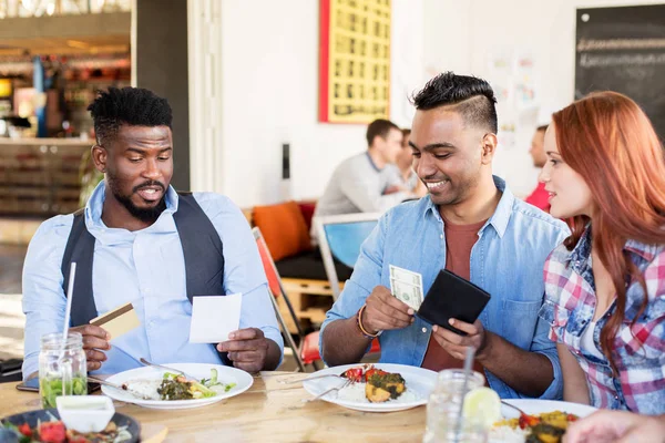 Amigos felices pagando la factura de comida en el restaurante —  Fotos de Stock
