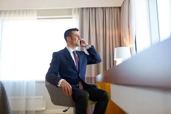 Businessman calling on smartphone at hotel room — Stock Photo, Image