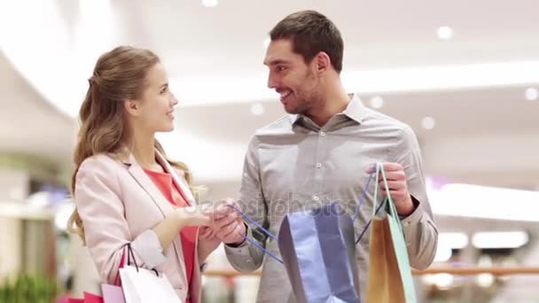 Feliz pareja joven con bolsas de compras en el centro comercial — Vídeos de Stock