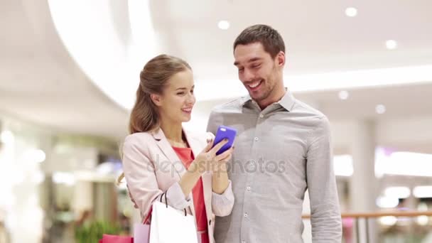 Casal com smartphone e sacos de compras no shopping — Vídeo de Stock