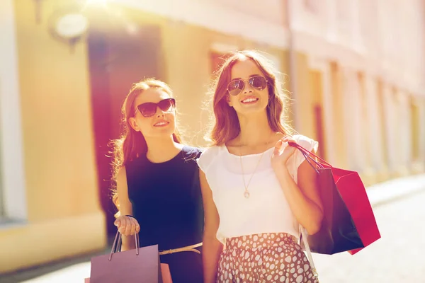 Mulheres felizes com sacos de compras andando na cidade — Fotografia de Stock