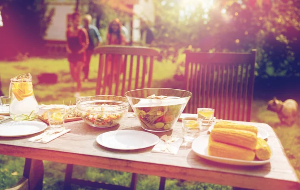 Ludzie przychodzą do tabeli z jedzeniem o letni ogródek — Zdjęcie stockowe