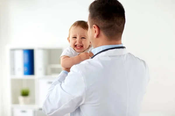 Gelukkig arts of kinderarts met baby bij kliniek — Stockfoto